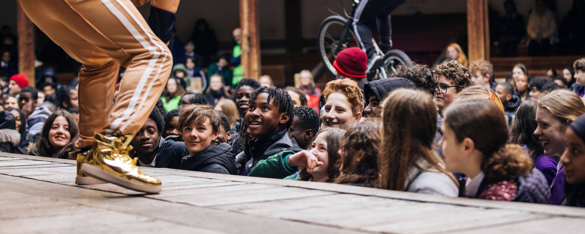 Audience members engaging with an actor on stage during a production of Playing Shakespeare with Deutsche Bank: Romeo and Juliet at the Globe Theatre in 2024.
