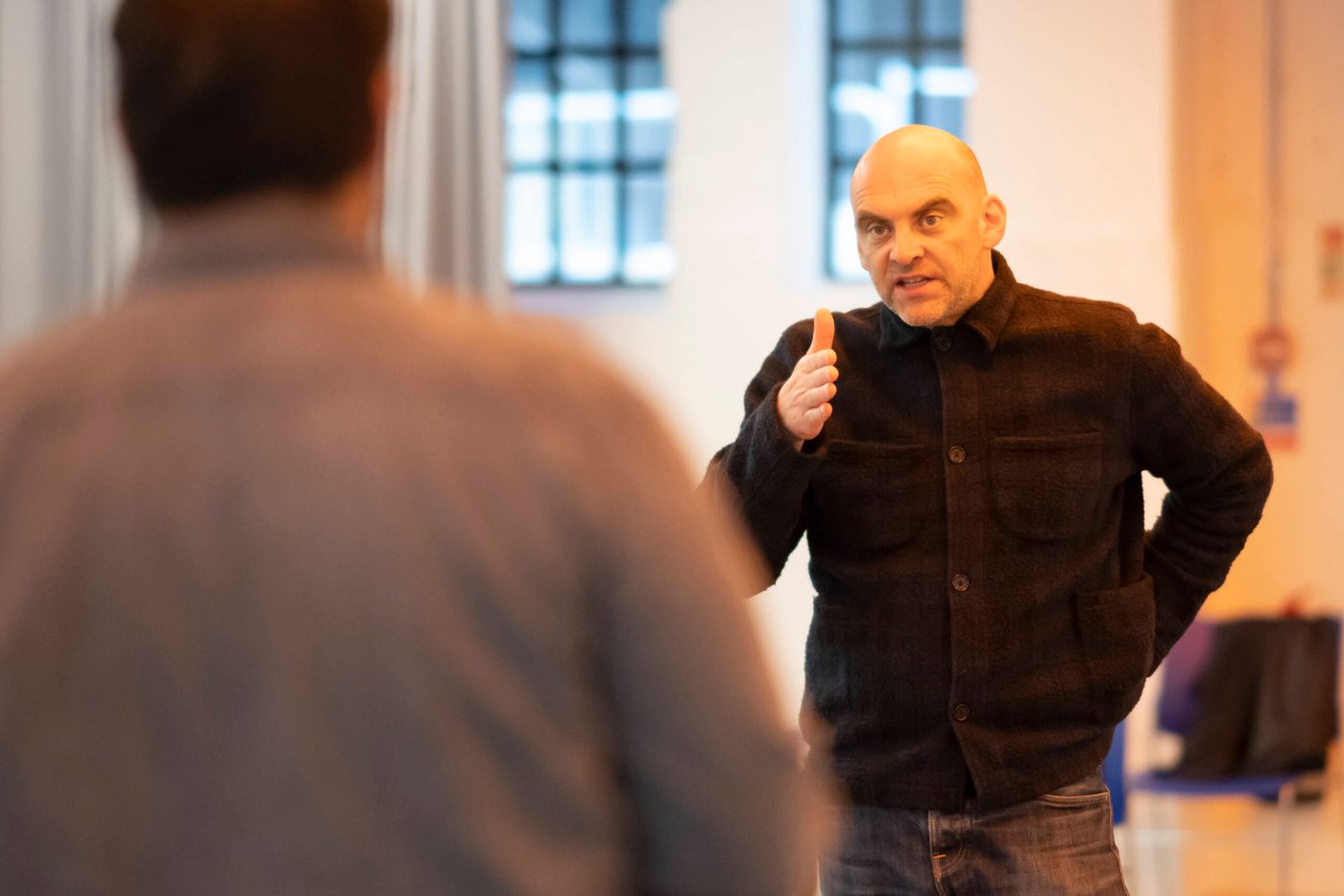 A director speaks to an actor who has his back facing the camera