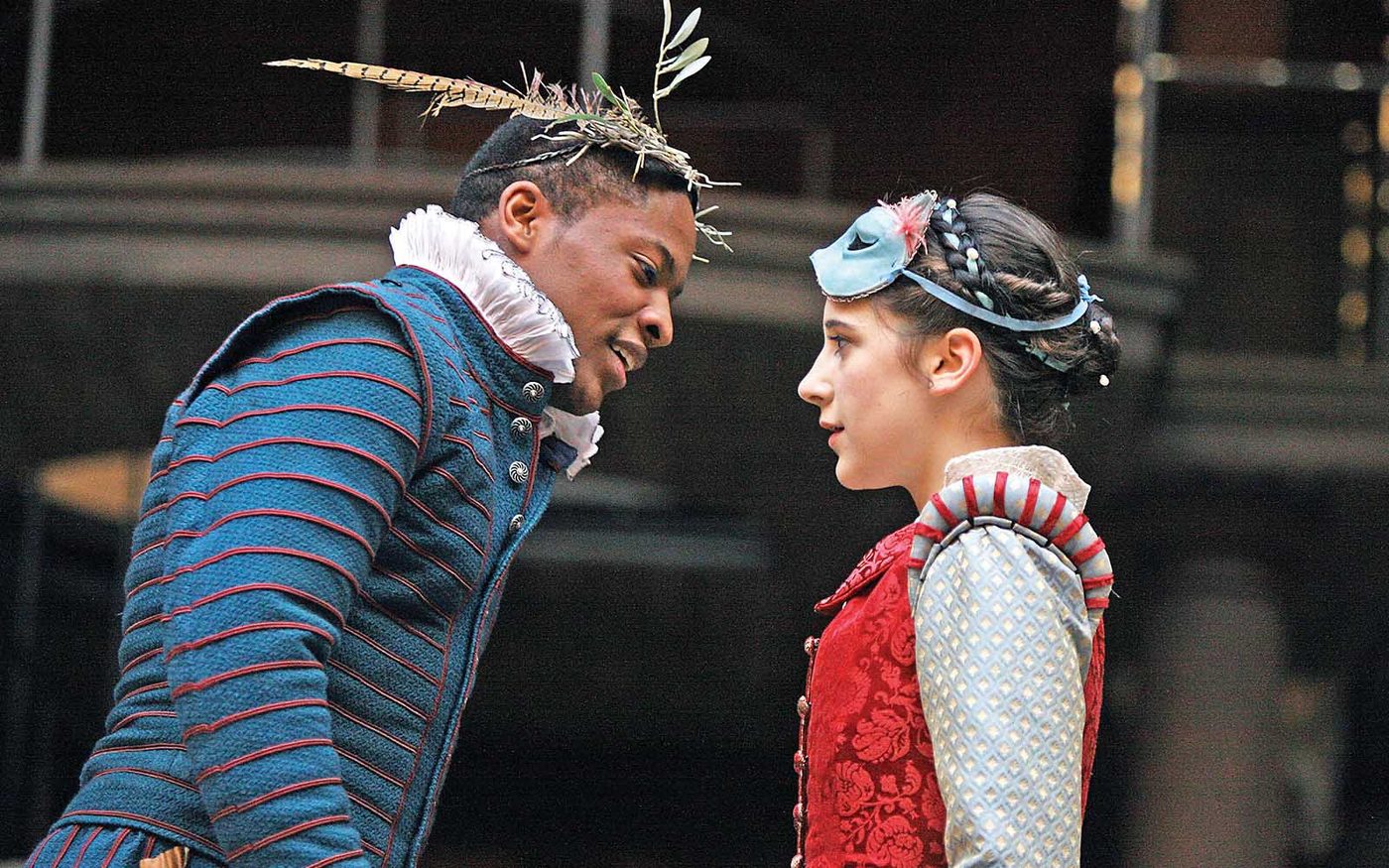 A man and woman stand facing each other on stage