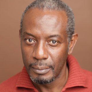 Tyrone Huggins wearing a red shirt and looking directly at the camera.
